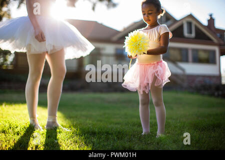 Happy young girl playing with her mother in their back yard.