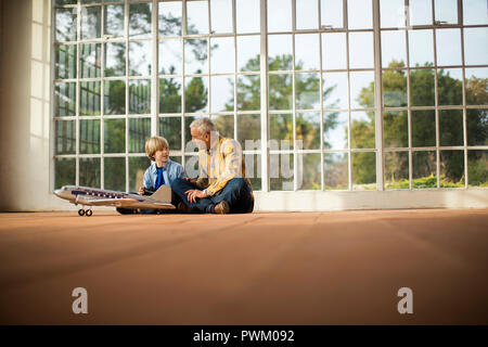 Happy senior man and young grandson playing with a model airplane. Stock Photo