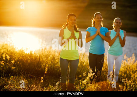 Three women practicing yoga in a rural field. Stock Photo
