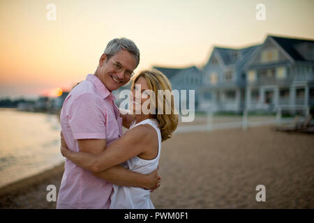 Portrait of a smiling middle aged couple embracing on a beach. Stock Photo