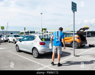 Man checking Goldcar hire car for damage before signing contract. Barcelona airport. Spain Stock Photo