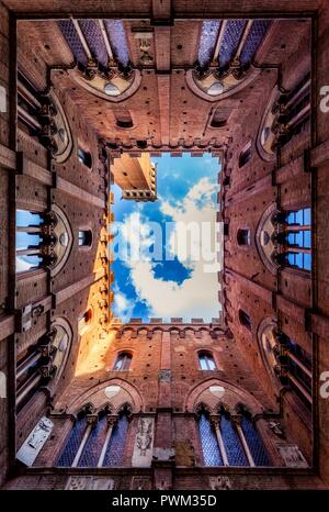 Siena is an incredible, winding city. Pictured is the courtyard of Cappella di Piazza, looking up towards the Tower of Mangia during a Tuscan summer. Stock Photo