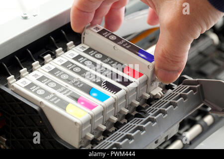 Man replacing an ink cartridge on a color inkjet printer (close up) - USA Stock Photo