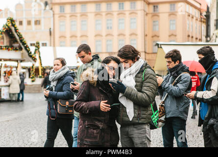 Prague, December 25, 2017: A young couple of tourists looks at a map on a cell phone on the main square in Prague during the Christmas holidays. Stock Photo