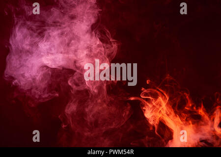 Textural background for creativity. Cloud of red and pink smoke on a black isolated background. Background from the smoke of vape Stock Photo