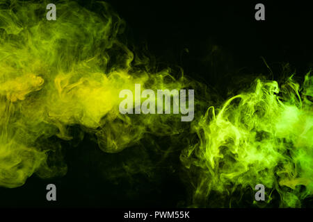 Textural background for creativity . Dense multicolored smoke of   green and yellow colors on a black isolated background. Background of smoke vape Stock Photo