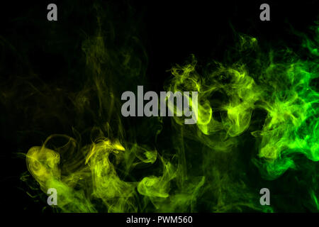 Textural background for creativity . Dense multicolored smoke of   green and yellow colors on a black isolated background. Background of smoke vape Stock Photo