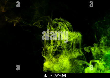Textural background for creativity . Dense multicolored smoke of   green and yellow colors on a black isolated background. Background of smoke vape Stock Photo