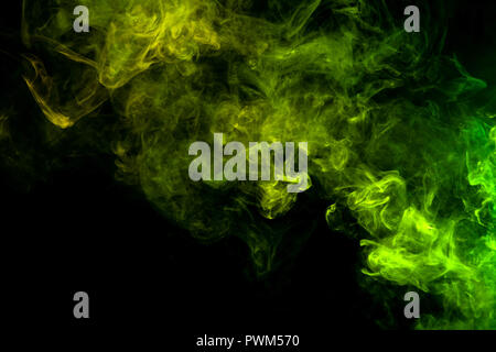 Textural background for creativity. Thick colorful smoke of green, yellow on a black isolated background. Background from the smoke of vape Stock Photo