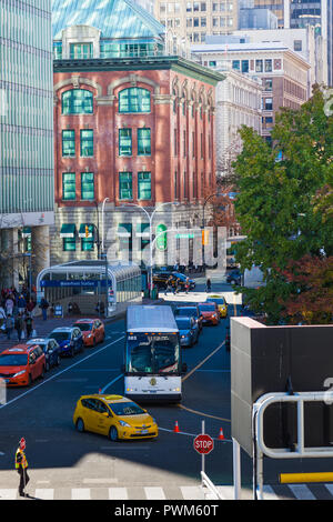 Intersection of Howe and Cordova streets in Vancouver with a red brick building illuminated by reflected light Stock Photo