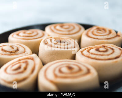 Raw dough preparation swedish cinnamon buns Kanelbullar with pumpkin spice ready to bake. Idea and recipe pastries - perfect cinnamon rolls in skillet. Copy space for text Stock Photo