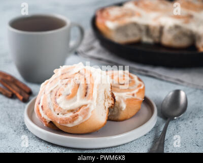 Vegan swedish cinnamon buns Kanelbullar with pumpkin spice,topping vegan cream cheese in plate with tea cup on table. Idea and recipe pastries - perfect cinnamon rolls. Copy space. Shallow DOF Stock Photo
