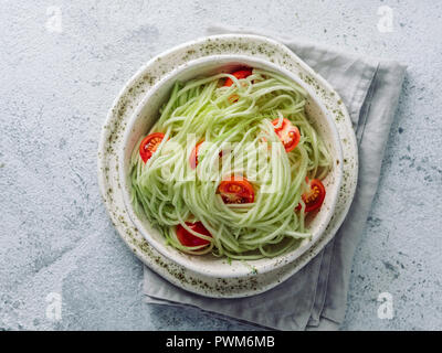 Zucchini noodles salad with cherry tomatoes. Vegetable noodles - green zoodles or courgette spaghetti salad ready-to-eat. Clean eating, raw vegetarian food concept. Copy space. Top view or flat lay. Stock Photo