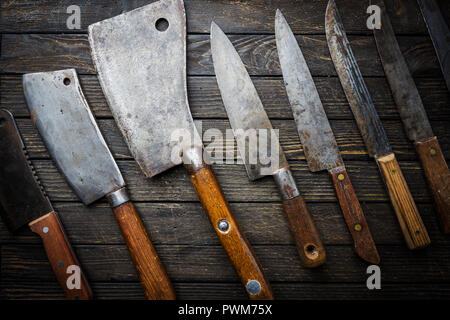 Set of Vintage kitchen knives and meat cleaver on dark wood background. Stock Photo