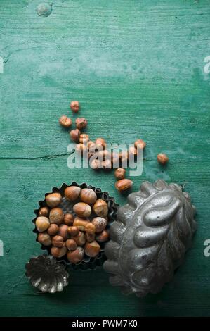 Hazelnuts, shelled and unshelled, in a baking tin on a rustic wooden surface Stock Photo