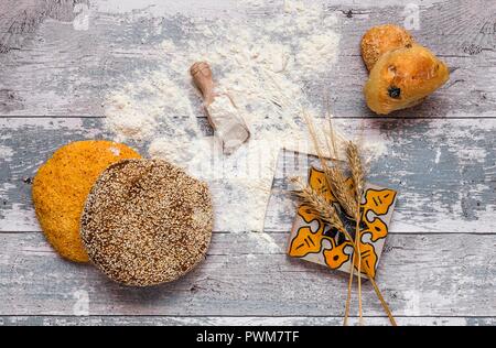 Assorted fresh breads on an old wooden table with flour and a napkin Stock Photo