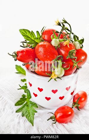 Cherry tomatoes in a vase decorated with red hearts Stock Photo