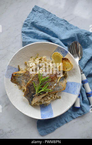 Fried fish fillets on risotto with green beans Stock Photo