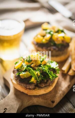 Grilled cheeseburgers with potatoes and beer on a chopping board Stock Photo