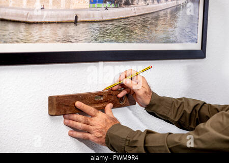 man using a spirit level on a white wall Stock Photo