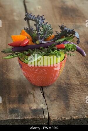 A vegetable bowl containing kale, chillis, pumpkin and long, thin aubergines Stock Photo