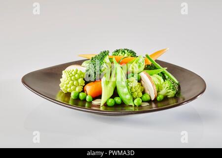 A plate of vegetables with Romanesco, broccoli, peas, spring onions, carrots, Brussels sprouts, mushrooms and mange tout Stock Photo
