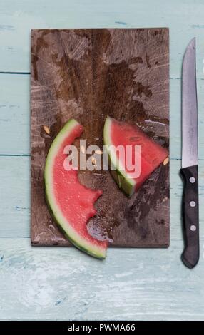 A half eaten slice of watermelon on a wooden board Stock Photo