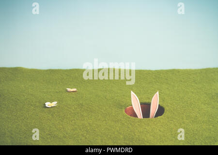 Tiny paper bunny hiding inside a hole Stock Photo