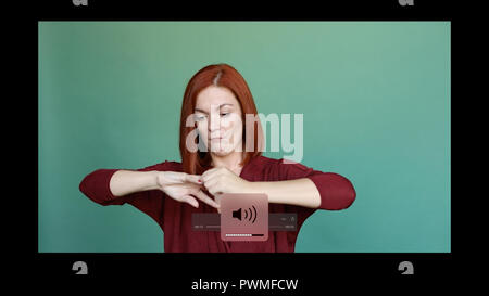 Red haired woman posing at studio on green background, pulls out ring from finger. Stock Photo