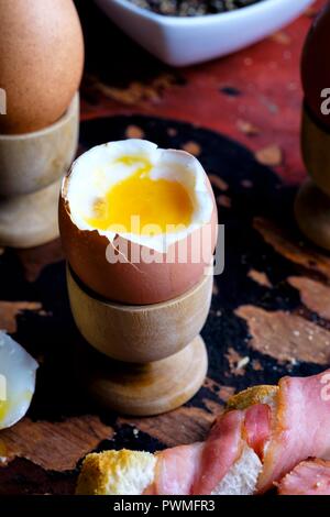 Soft boiled eggs with bacon-wrapped toast Stock Photo