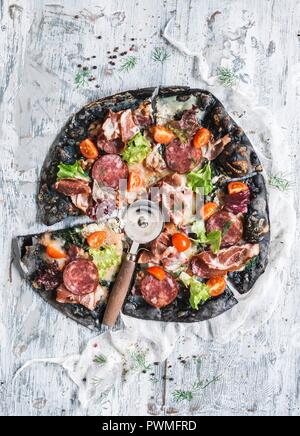 Black pizza with ham, sausage, bacon and vegetables Stock Photo