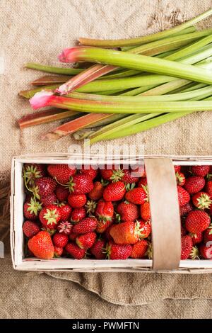 Strawberries in a wooden basket next to rhubarb Stock Photo
