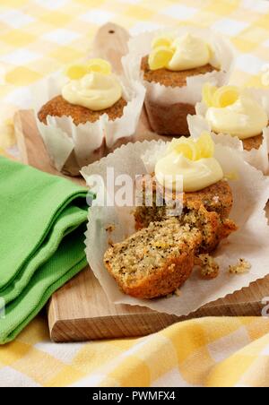Several Seeded Lemon drizzle cupcakes in white paper cupcake cases on a wooden board Stock Photo