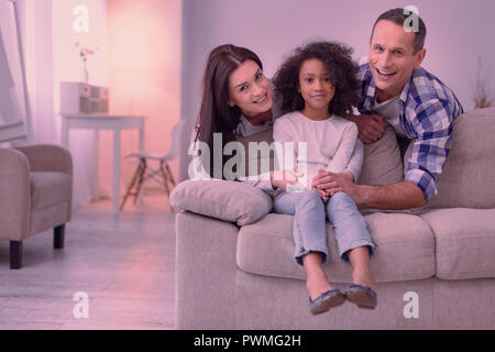 Delighted joyful parents standing behind their daughter Stock Photo