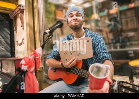Pleased male musician waiting for tips after play Stock Photo