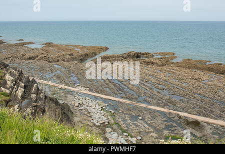 Beach at Westward Ho! in North Devon, England at low tide, showing rock table and large shingle boulders. Stock Photo