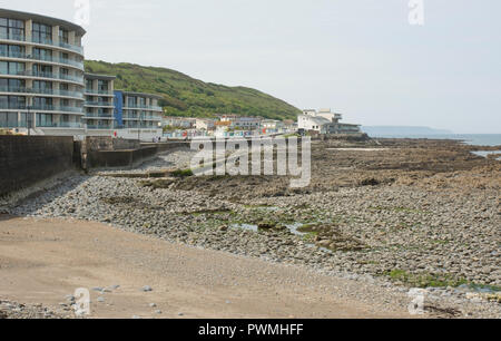 Apartment buildings and houses on the seafront at Westward Ho! in North Devon, England. With people walking and stony beach. Stock Photo