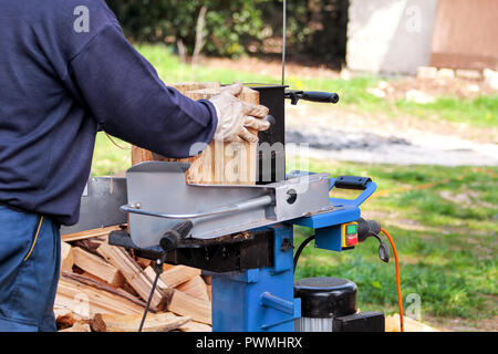 Saw cutting wood for winter. A man cutting firewood for the winter using a modern machine lumber saw. Wood industry. Heating season, winter season. Stock Photo