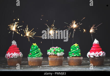 Vanilla cupcakes with christmas decoration and sparklers on dark background; holiday background with copy space Stock Photo
