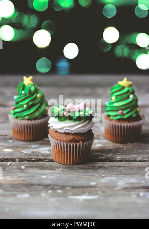 Vanilla cupcakes with christmas decoration, on dark background with colorful christmas lights Stock Photo