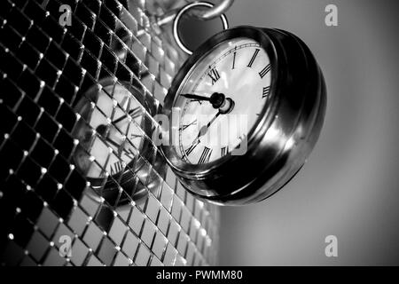 Close up arty shot of a metal large pocket watch clock next to a silver disco ball in black and white Stock Photo