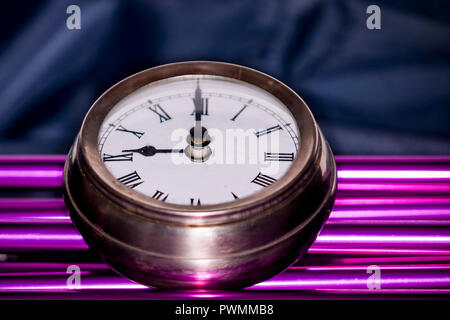 Arty shot of a metal large pocket watch clock on purple pipes Stock Photo