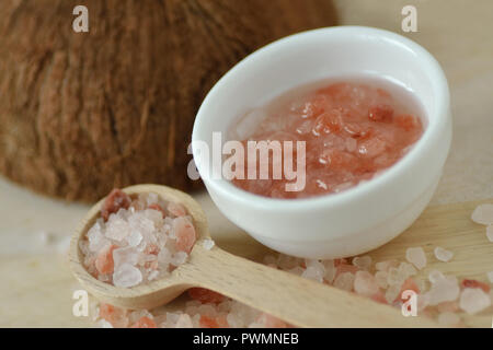 Homemade face scrub made out of Himalayan pink salt and coconut oil in a bowl with wooden spoon Stock Photo