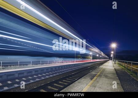 Light trails of passenger train commuting to railroad station at night.