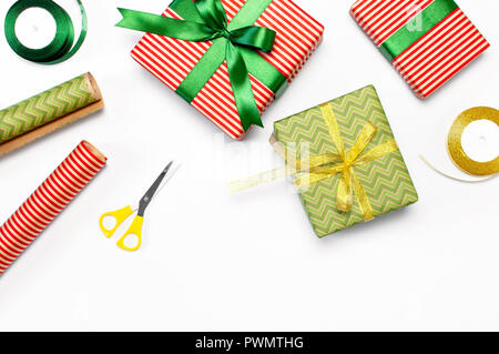 Gift boxes, packing paper, scissors, ribbon on red background