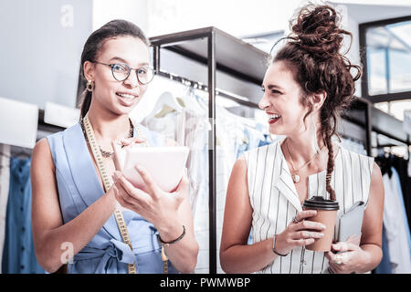 Smiling woman with nice hairstyle coming to her friend working in showroom Stock Photo