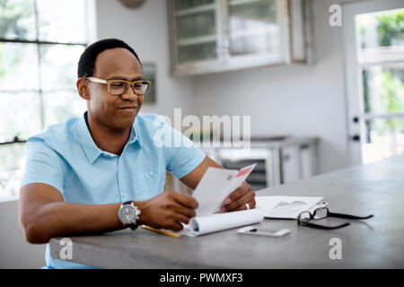 Man reading mail in kitchen. Stock Photo