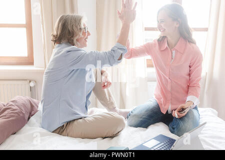Mother and daughter working together giving high-five Stock Photo