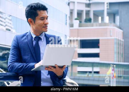 Asian businessman carry notebooks stand outdoor and act thinking,have space for idea. Stock Photo