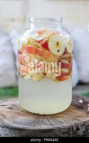 Apple vinegar making - apple pieces floating in a glass in rustic interior